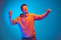 Studio shot of young emotional man, student dancing isolated over blue studio background. Action, sport, fashion Royalty Free Stock Photo