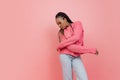 Studio shot of young excited girl with afro hairdo in casual style outfit having fun isolated on pink background Royalty Free Stock Photo