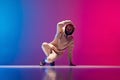 Studio shot of young flexible sportive man dancing breakdance in white outfit on gradient pink blue background. Concept