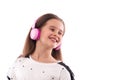 Studio shot of a young girl wearing white blouse on a white background. She is standing in pink headphones listening to music Royalty Free Stock Photo