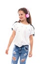 Studio shot of a young girl wearing white blouse and jeans on a white background. She is standing in pink headphones listening Royalty Free Stock Photo