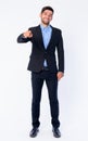 Full body shot of happy young bearded Persian businessman pointing at camera Royalty Free Stock Photo