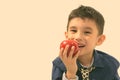 Studio shot of cute happy boy smiling and eating apple Royalty Free Stock Photo