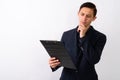 Studio shot of young handsome businessman thinking while looking Royalty Free Stock Photo