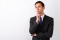 Studio shot of young handsome businessman thinking while looking Royalty Free Stock Photo