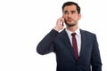 Studio shot of young handsome businessman thinking while looking Royalty Free Stock Photo