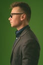 Studio shot of young handsome businessman against green background Royalty Free Stock Photo