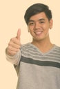 Close up of young happy Asian man smiling and giving thumb up