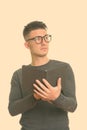 Studio shot of young handsome man holding book while thinking Royalty Free Stock Photo