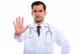 Studio shot of young handsome man doctor showing stop hand sign Royalty Free Stock Photo