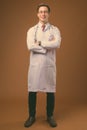 Young handsome man doctor against brown background Royalty Free Stock Photo