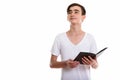 Studio shot of young handsome Persian teenage boy holding book w Royalty Free Stock Photo