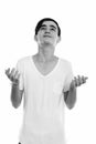 Studio shot of young handsome Persian teenage boy shrugging shoulders while looking up Royalty Free Stock Photo