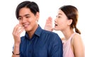 Studio shot of young happy Asian couple smiling with woman whisp Royalty Free Stock Photo