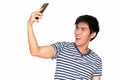 Studio shot of young happy Asian man taking selfie with mobile phone isolated against white background Royalty Free Stock Photo