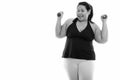 Studio shot of young happy fat Asian woman smiling and raising both dumbbells Royalty Free Stock Photo