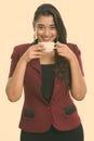 Studio shot of young happy Indian businesswoman smiling while drinking coffee Royalty Free Stock Photo