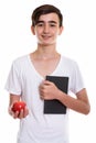 Studio shot of young happy Persian teenage boy smiling while hol Royalty Free Stock Photo