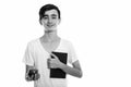 Studio shot of young happy Persian teenage boy smiling while holding book and red apple Royalty Free Stock Photo