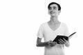 Studio shot of young happy Persian teenage boy smiling and holding book while thinking Royalty Free Stock Photo