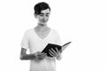 Studio shot of young happy Persian teenage boy smiling while reading book Royalty Free Stock Photo