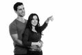 Thoughtful young happy couple smiling while hugging each other with woman pointing at distance Royalty Free Stock Photo