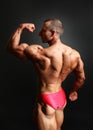 Studio shot of young male bodybuilder posing, showing his biceps Royalty Free Stock Photo