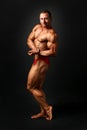 Studio shot of young male bodybuilder posing, showing side bicep Royalty Free Stock Photo