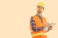 Studio shot of young man construction worker writing on clipboard while thinking Royalty Free Stock Photo