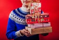 Studio shot of a young man in Icelandic sweater holding a heap of gift boxes. Christmas or New Year celebration concept.