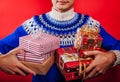 Studio shot of a young man in Icelandic sweater holding a heap of gift boxes. Christmas or New Year celebration concept.