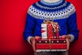 Studio shot of a young man in Icelandic sweater holding a heap of gift boxes. Christmas or New Year celebration concept.