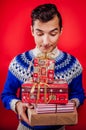 Studio shot of a young man in Icelandic sweater holding a heap of gift boxes. Christmas or New Year celebration concept.