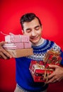 Studio shot of a young man in Icelandic sweater holding a heap of gift boxes. Christmas or New Year celebration concept.