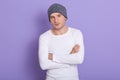 Studio shot of young man standing with hands folded wearing white casual shirt and gray cap. Copy space for advertisment or Royalty Free Stock Photo