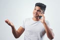 Lets get to know each other. Studio shot of a young man talking on his cellphone while standing against a white Royalty Free Stock Photo