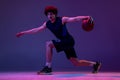 Studio shot of young muscular basketball street player dribbling ball isolated on purple background in neon. Concept of Royalty Free Stock Photo