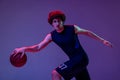 Studio shot of young muscular basketball street player dribbling ball isolated on purple background in neon. Concept of Royalty Free Stock Photo