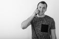 Studio shot of young happy muscular man smiling while talking on mobile phone against white background Royalty Free Stock Photo