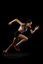 Studio shot of young muscular woman running isolated on black background. Sport, track-and-field athletics, competition Royalty Free Stock Photo