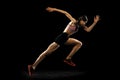 Studio shot of young muscular woman running isolated on black background. Sport, track-and-field athletics, competition Royalty Free Stock Photo