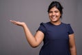 Young overweight beautiful Indian woman against gray background Royalty Free Stock Photo