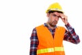 Studio shot of young Persian man construction worker looking str