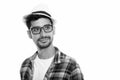 Studio shot of young Persian man thinking while wearing eyeglasses and hat Royalty Free Stock Photo