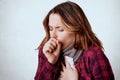 Studio shot of young sick caucasian woman wearing scarf and checkered shirt, coughin, being ill with grippe or coronavirus, posing