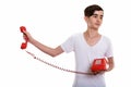 Studio shot of young stressed Persian teenage boy holding old te Royalty Free Stock Photo