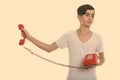 Studio shot of young stressed Persian teenage boy holding old telephone away Royalty Free Stock Photo