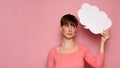 Studio shot of a young woman with a bizarre facial expression, holding a white empty banner in the form of a cloud on a Royalty Free Stock Photo