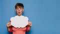 Studio shot of a young woman with a bizarre facial expression, holding a white empty banner in the form of a cloud on a Royalty Free Stock Photo