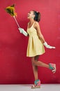 Dust the chores away. Studio shot of a young woman holding a feather duster against a red background.